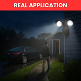 Person walking towards a house with a security light on a dark night.
