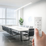 Hand holding a remote control in a modern conference room with a large table and chairs.