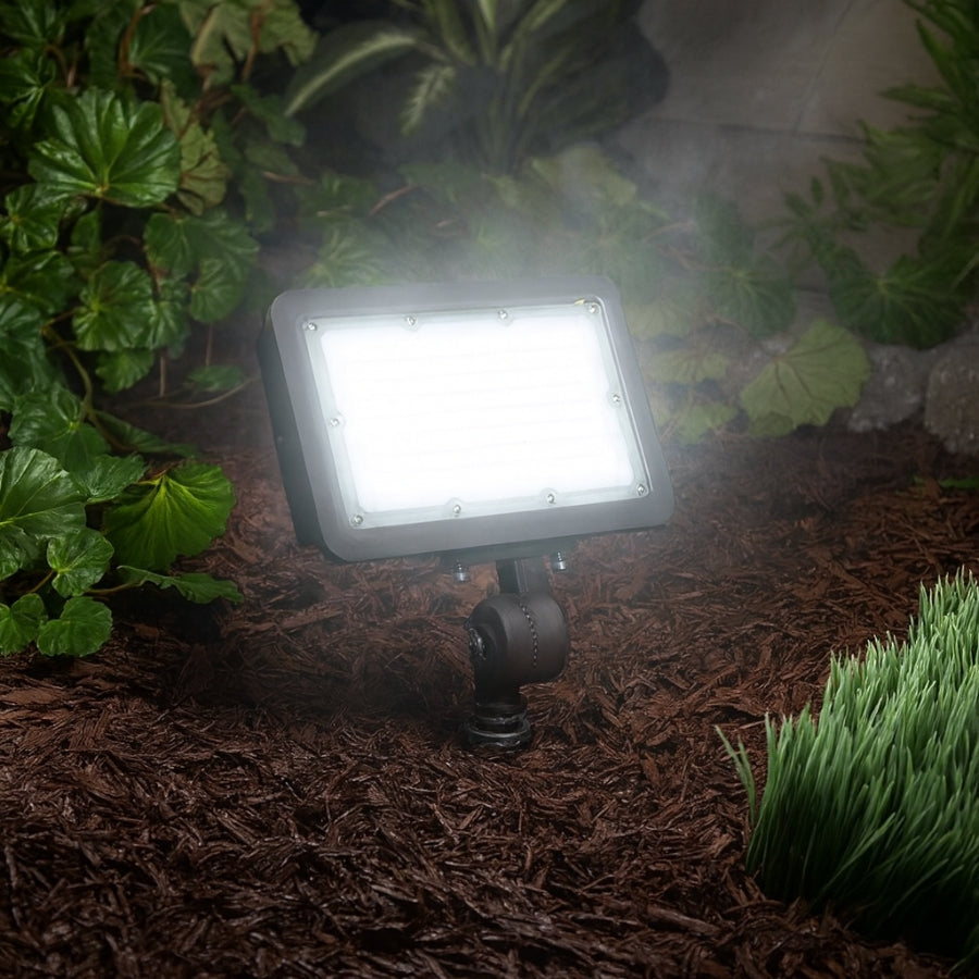 Outdoor LED flood light on a garden bed with plants around