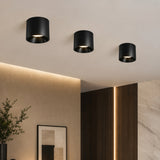 Three black ceiling lights on a beige ceiling with a modern interior setting.