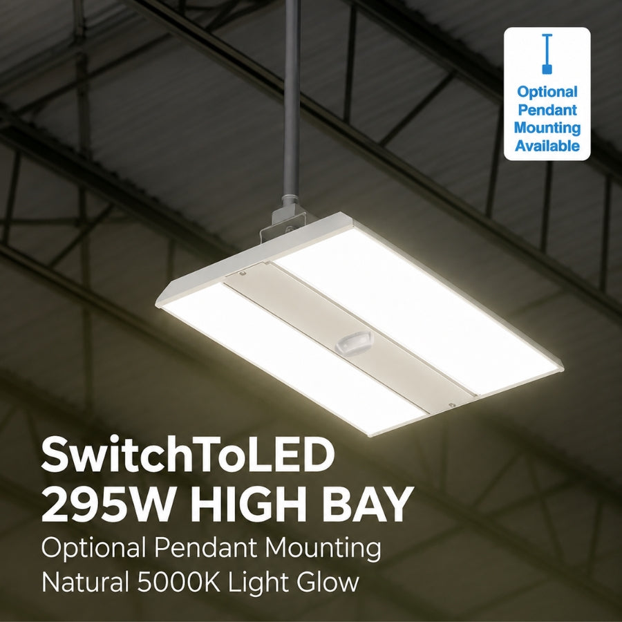 A rectangular high-bay LED pendant light suspended from a ceiling in an industrial warehouse setting. The light has a white frame and is emitting a bright white glow.